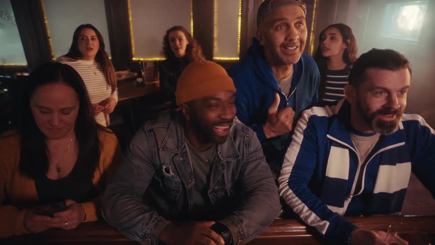 A group of friends in a pub watching a game with excitement then suddenly feeling disappointed
