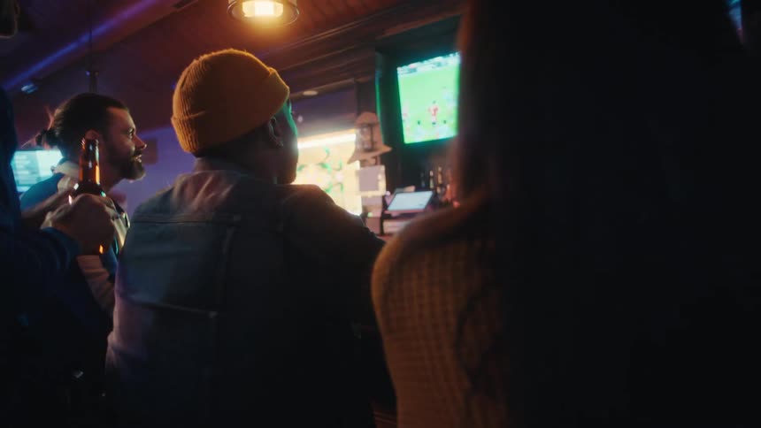 People in the bar are being served drinks while watching a sports game