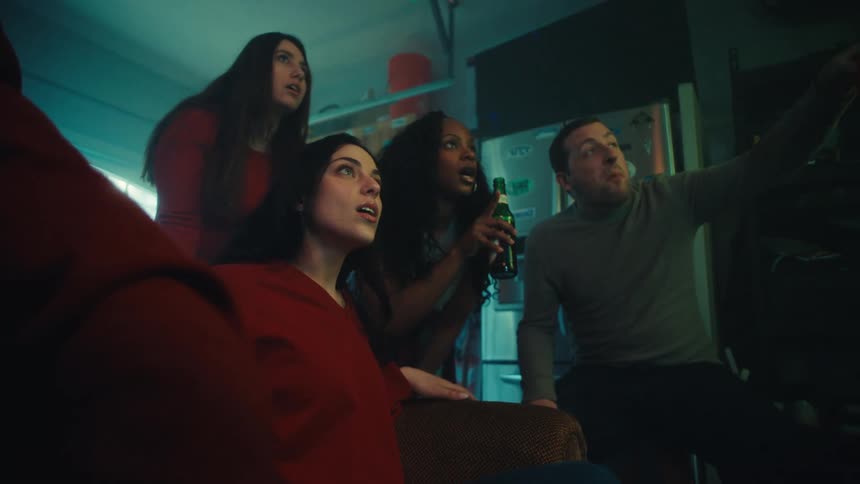Group of people gathered in a home setting watching something offscreen