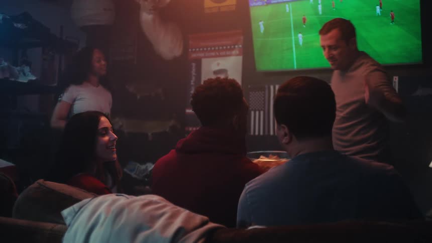 A group of people watching sports on a tv in a room