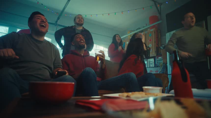 A group of people cheering while watching sports on tv