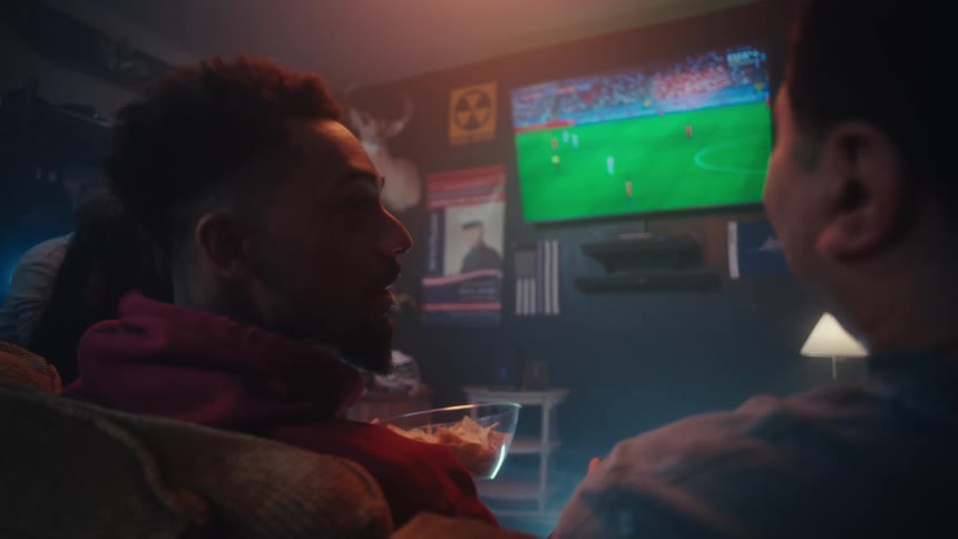 Group of friends talking while watching a soccer game in the television indoors