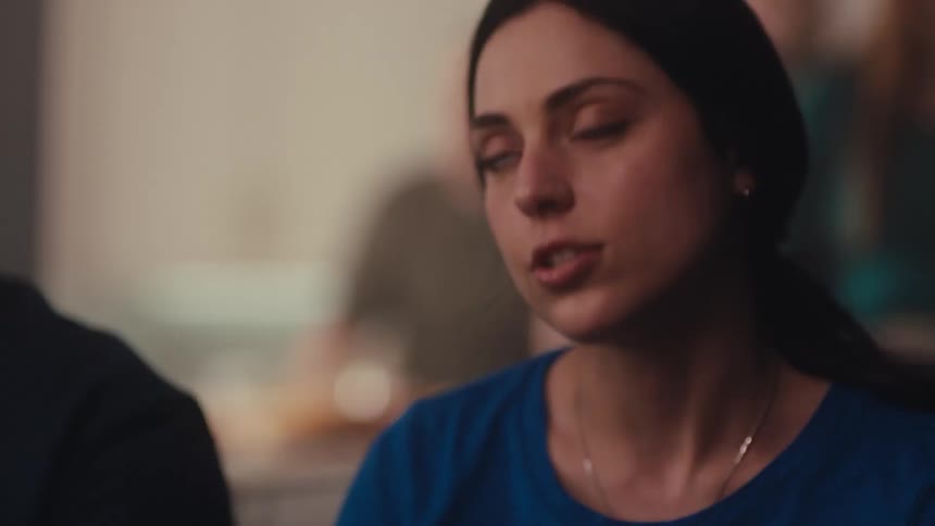 Woman in closeup looks at something offscreen with a blurred indoor background