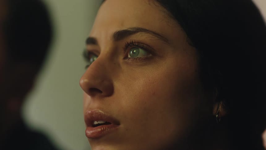 The woman is watching something and blinking