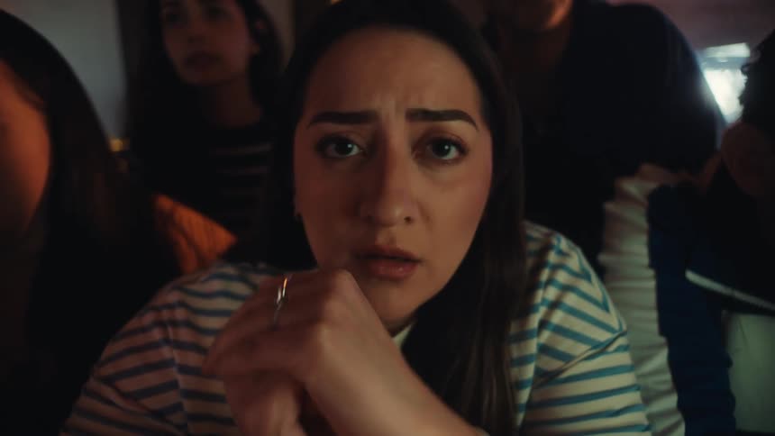 A young woman wearing a striped shirt watches a game with a look of intense focus that quickly turns to disappointment and frustration