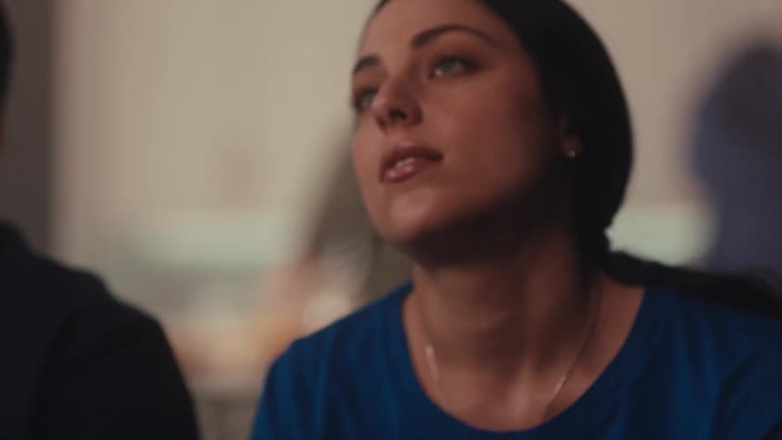 A woman with dark hair and lightcolored eyes looks upward with an expression of intense focus and anticipationmidway through the video she briefly closes her eyes and lowers her head in a moment of relief or disappointment before looking back up with
