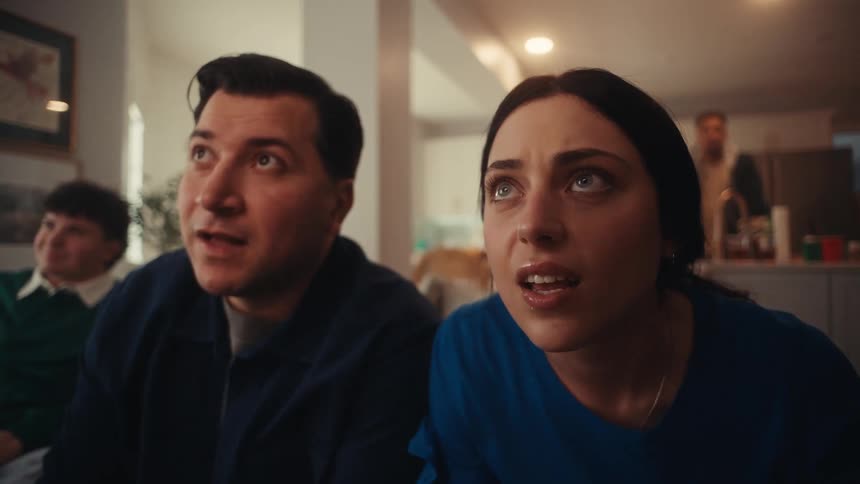 The man and woman are excited as they watch something at a party
