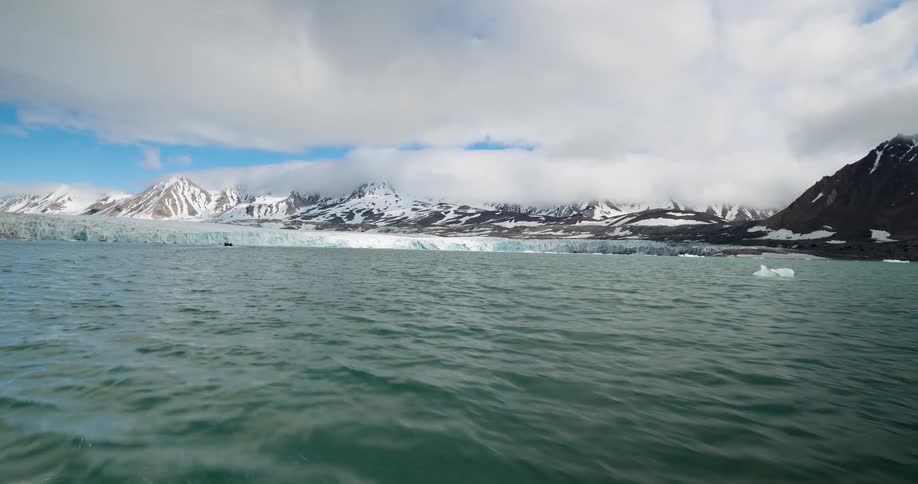 Sea ice floats by the shore of the mountains