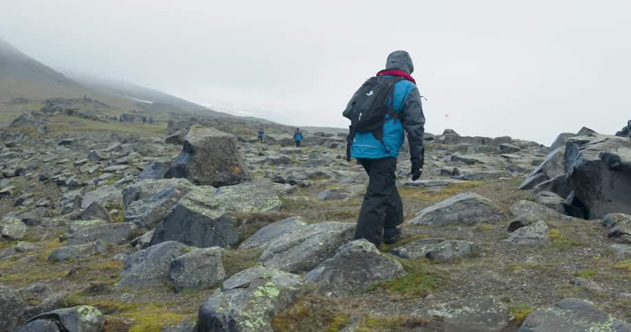 People are hiking over the rocks on the foggy mountain