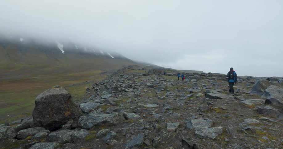 The man is hiking towards the mountain on a foggy day