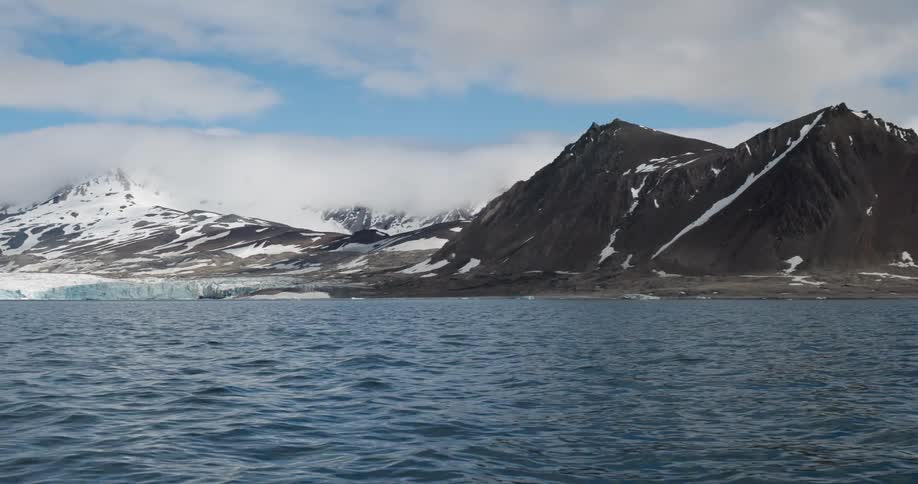 Snow on mountains along the coast as water ripples and waves