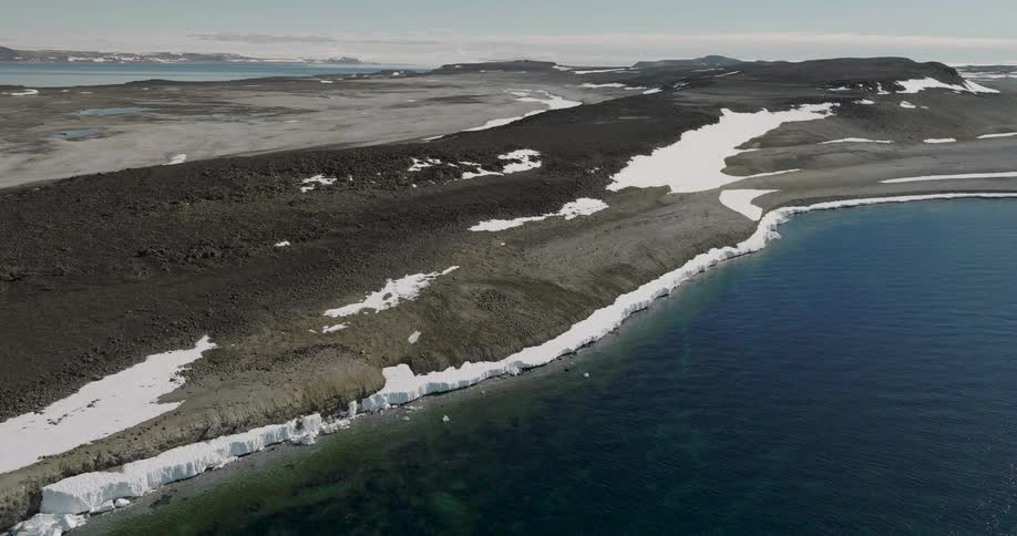 Snow and ice along the coast with mountains across the land