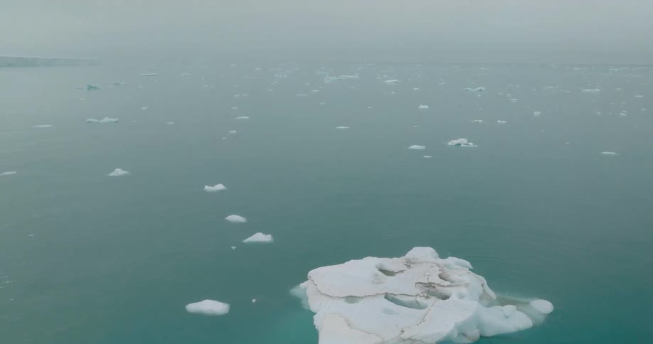 Ice covers an island as small icebergs float in the water nearby