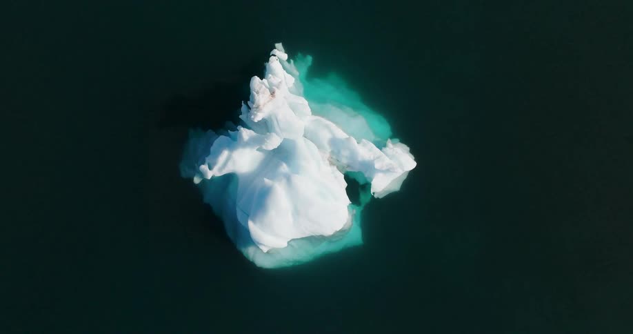 Aerial view of a stunning lone iceberg floating in dark arctic waters at night
