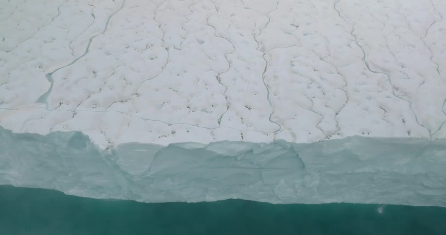 A tall iceberg rising out of the arctic sea at midday