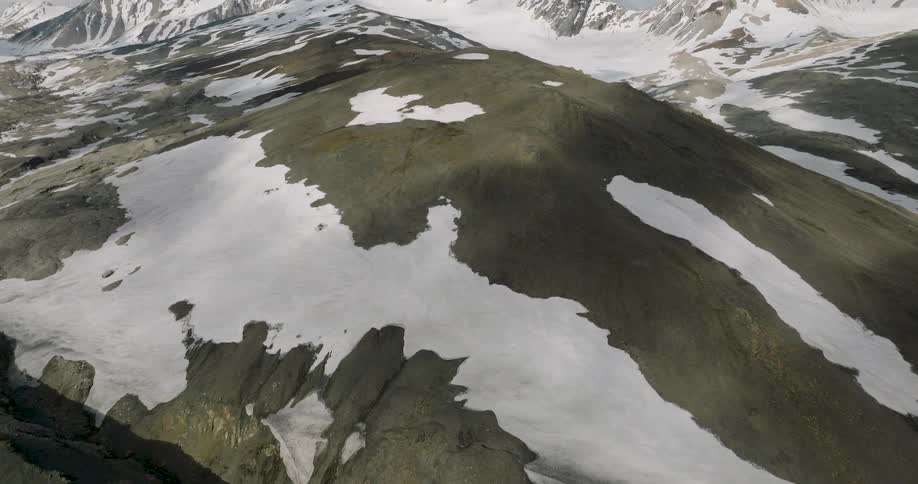 Aerial view of snow covered arctic mountains and barren ridgelines stretching across the horizon
