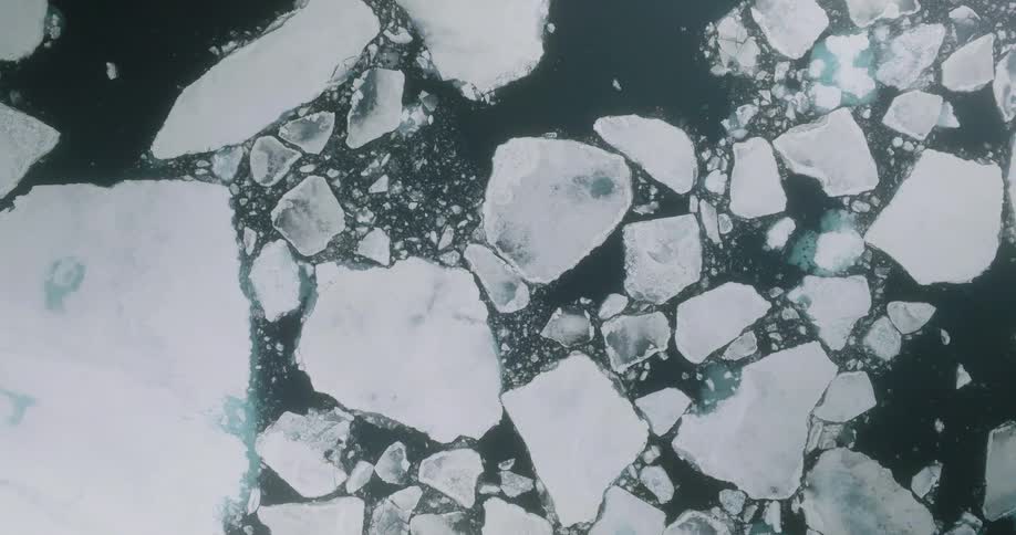Fragmented ice floes floating on dark water seen from above
