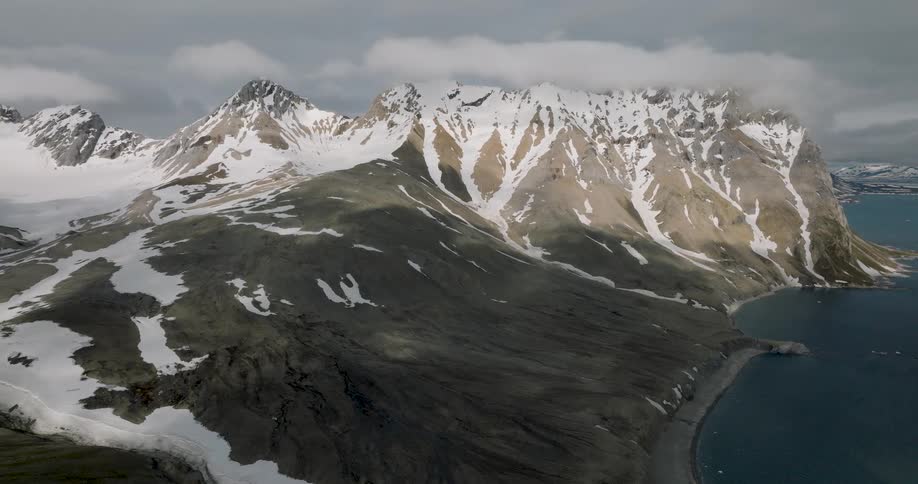 Steep mountains with partially snowcovered slopes beside a deepwater coastal inlet