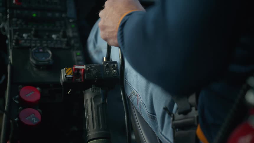 Curved black cable is positioned behind the main control stick trailing down toward the floor of the cockpit it follows a slightly bowed path likely serving as a hydraulic or electrical lead for the seat or the secondary control systems
