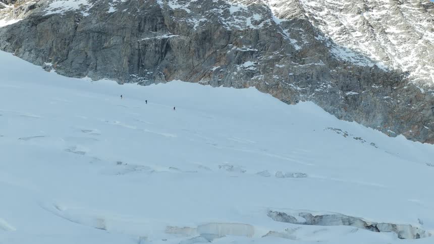 The people are hiking on the snow covered slope