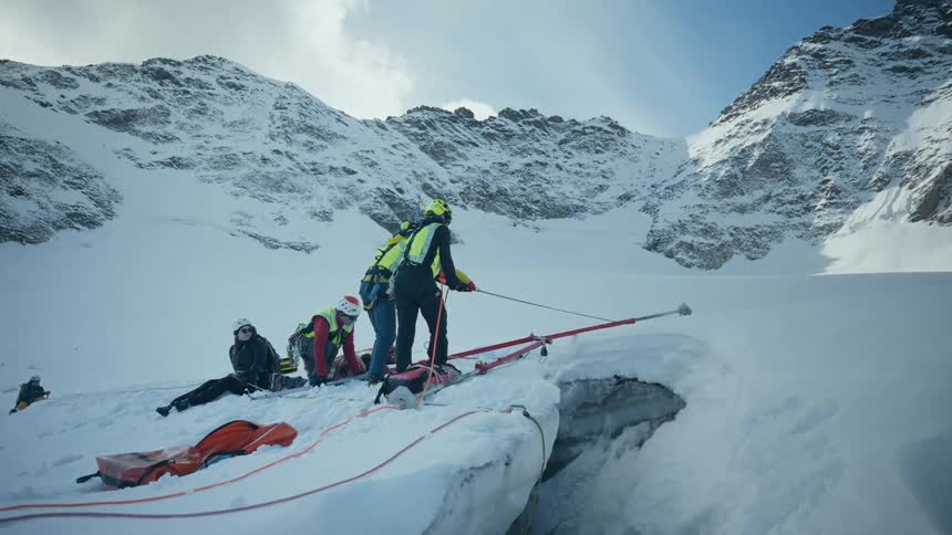 Rescue team sets up an anchoring system over a glacier crevasse in an alpine environment