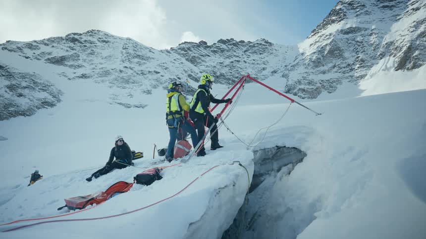 Rescue team operates over a glacier crevasse using ropes and a stretcher