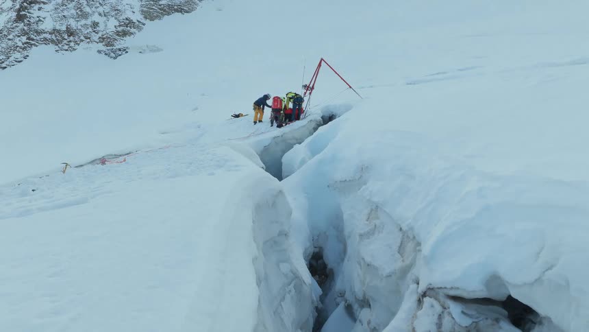 Rescue team works on extracting a victim from a snowcovered glacier crevasse
