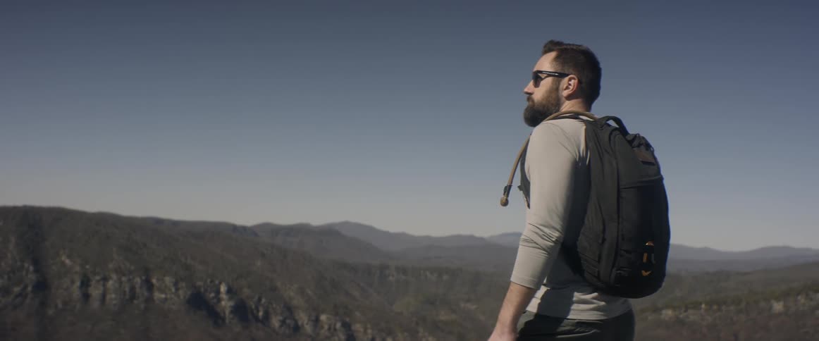 A hiker with a backpack overlooks a valley