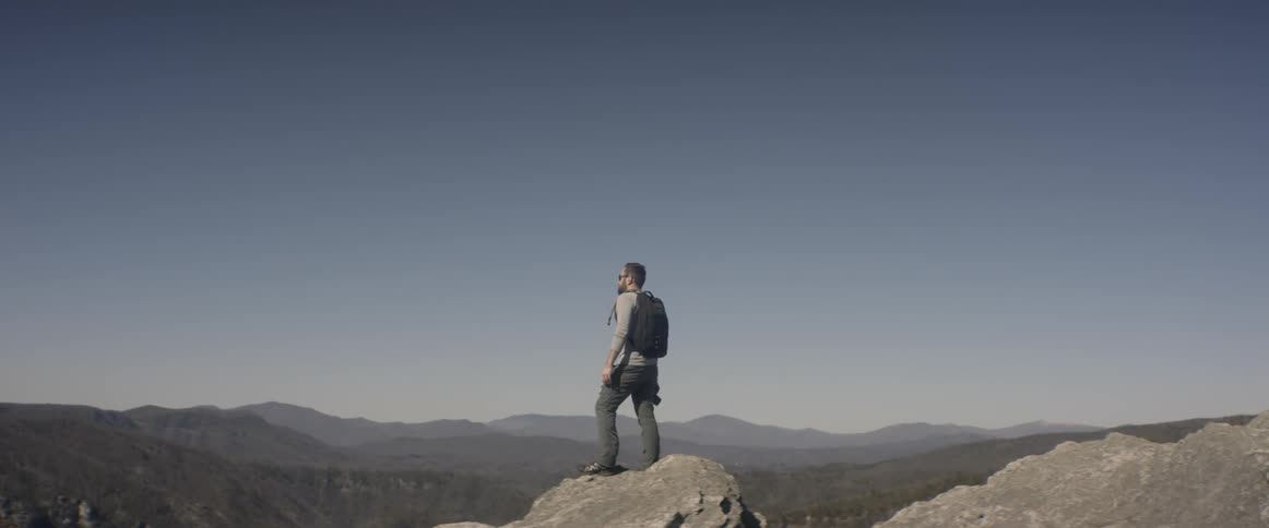 A man stands on a mountain looking at the view