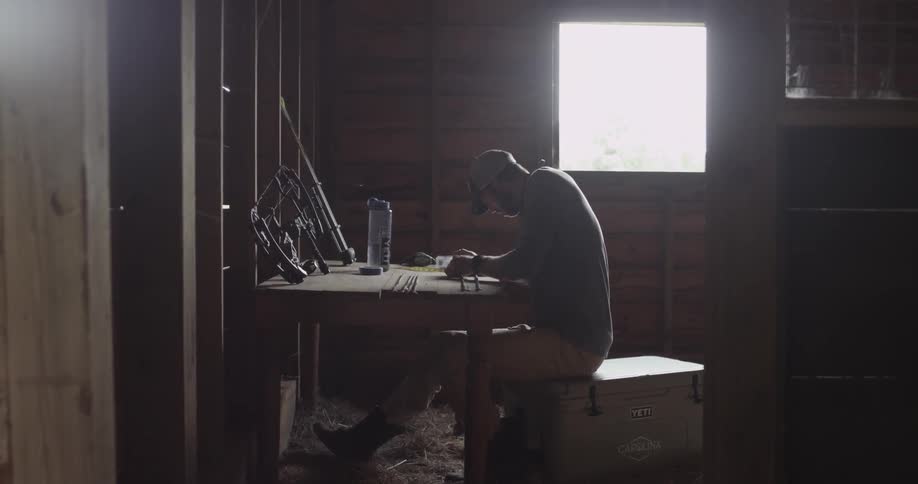 A man assembles arrows at a table