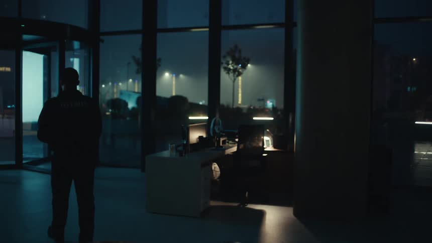 Security guard stands in a dark room pouring coffee into a mug and walks out the door