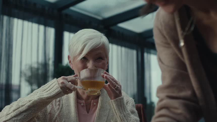 A woman pouring a glass of tea for another woman