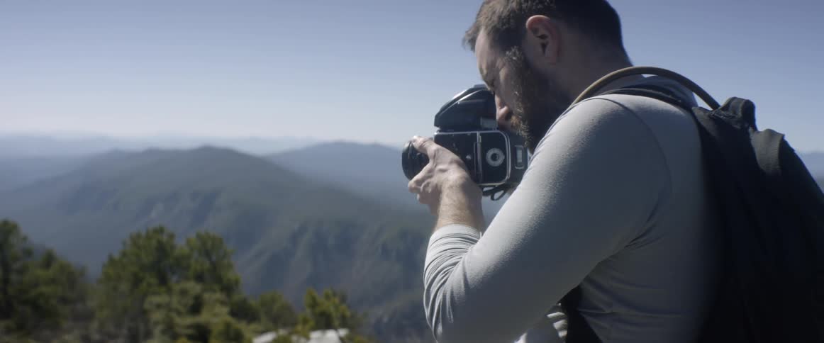 A photographer takes a photograph atop a mountain