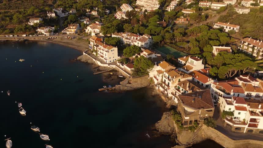 Aerial view of a coastal village with terracottaroofed houses along a rocky cove