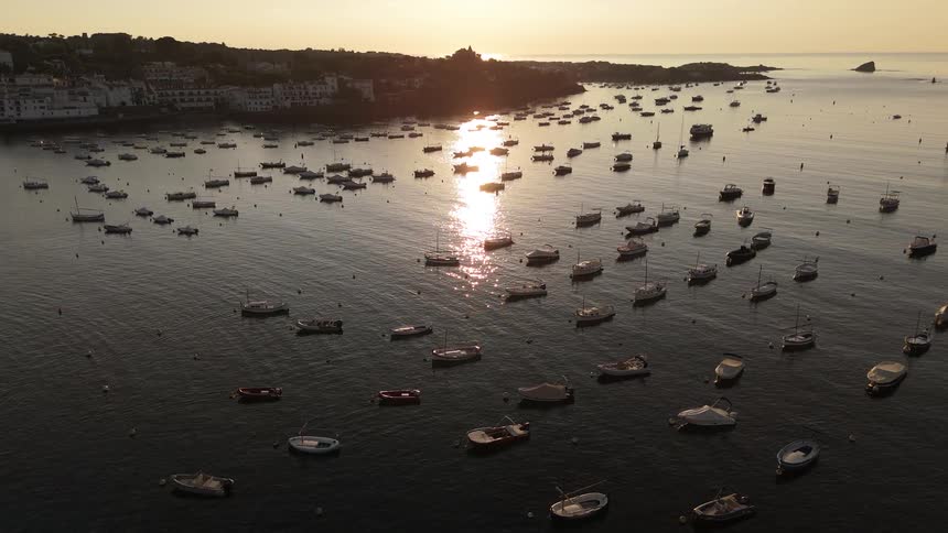 Aerial view of a dozens of small boats anchored in a peaceful bay at sunset