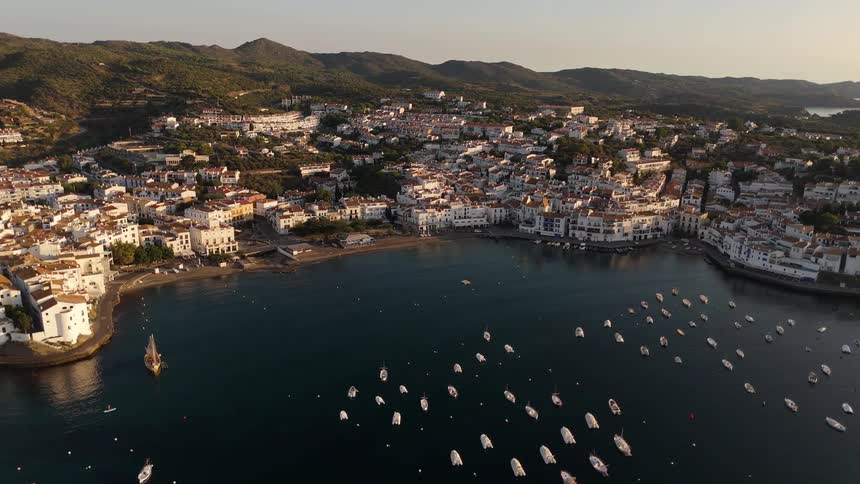 Aerial of boats in the body of water and waterfront buildings at sunset