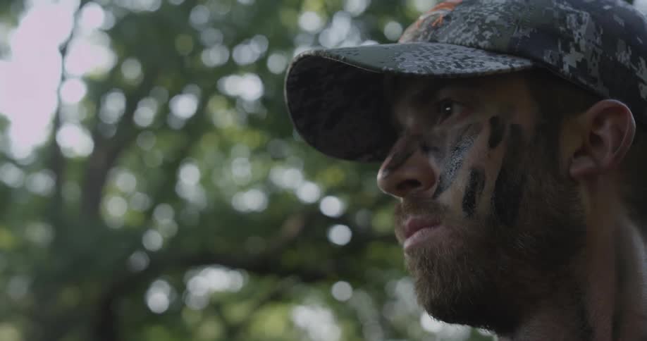 Man with camouflage face paints standing still out in nature
