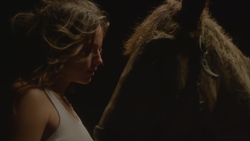 A woman leans in to rest her forehead against a horses head