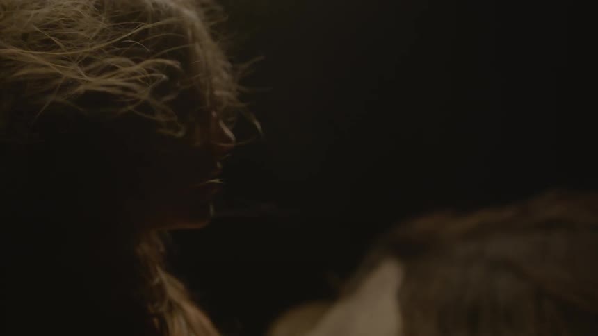 Adult woman petting and looking in admiration at a horse indoors