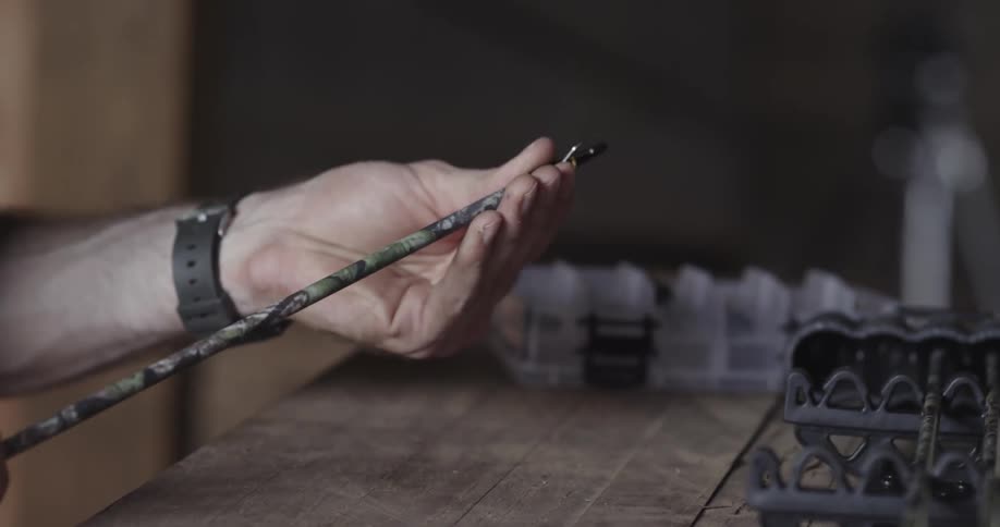 A hunter adjusts the tip of an arrow