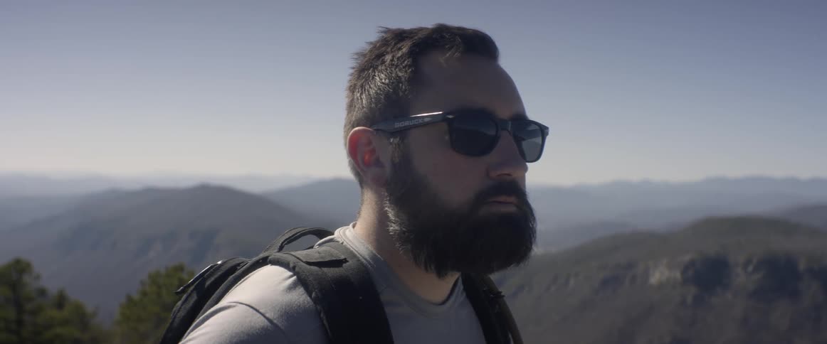 A hiker stands in the mountains with a backpack
