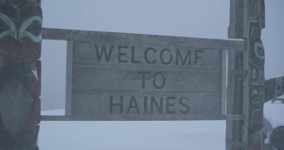 Snow is blowing sideways on a wooden town sign