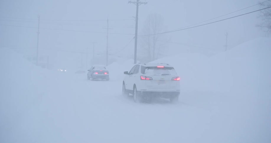 Vehicles drive through a snowstorm in the winter