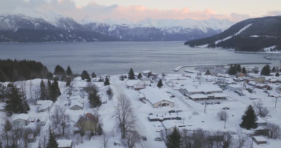 Aerial view of a snowcovered town by a lake surrounded by mountains