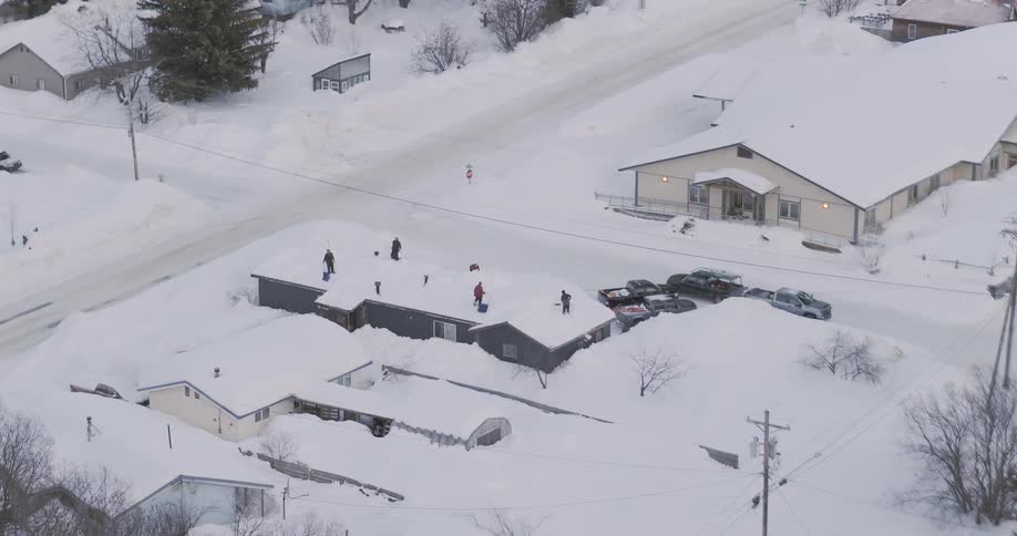 Aerial view shows people on a snowcovered rooftop in a residential area during winter