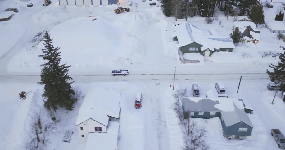 Truck travels on a road in a snow covered neighborhood on a winter day