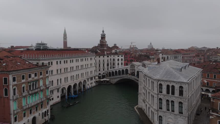 Urban canal with historic buildings a bridge in the background and gondolas in transit