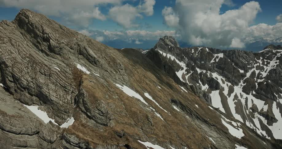 Rocky mountain range with patches of snow under a partly cloudy sky