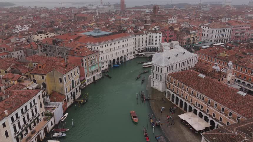 Aerial view of a central canal surrounded by historic buildings and moving boats