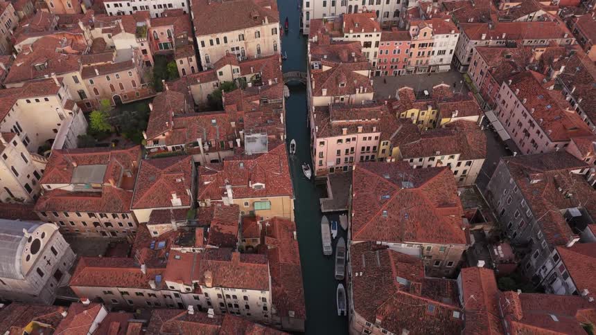 Boats travel along a channel passing between apartment buildings during the daytime